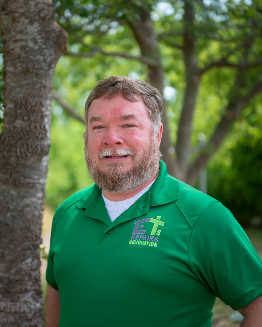 Smiling man with a beard and short hair wearing a green polo shirt