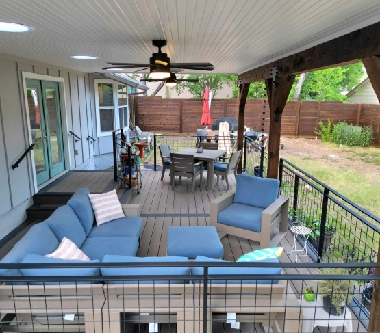 Spacious covered deck with blue patio furniture and ceiling fan. Outdoor Living Remodel in Austin, TX.