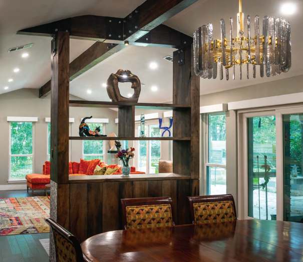 Dining room with rustic wood shelving, a modern chandelier, and a view into a bright living area with orange accents. Dining and Living Room Renovation in Austin, TX.