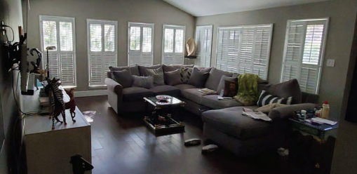 A cozy living room featuring a couch and a large window letting in natural light.  Before dining and Living Room Renovation in Austin, TX.