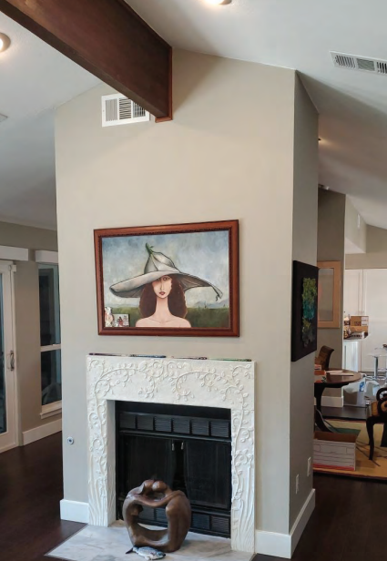Living room with white ornate fireplace, framed portrait above it, and wooden sculpture. Dining and Living Room Renovation in Austin, TX.