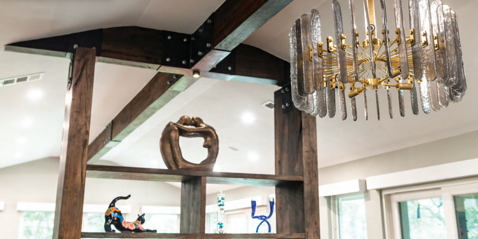 Modern chandelier with glass panels hanging near exposed wooden beams and decorative sculptures on open wooden shelving.  Dining and Living Room Renovation in Austin, TX.